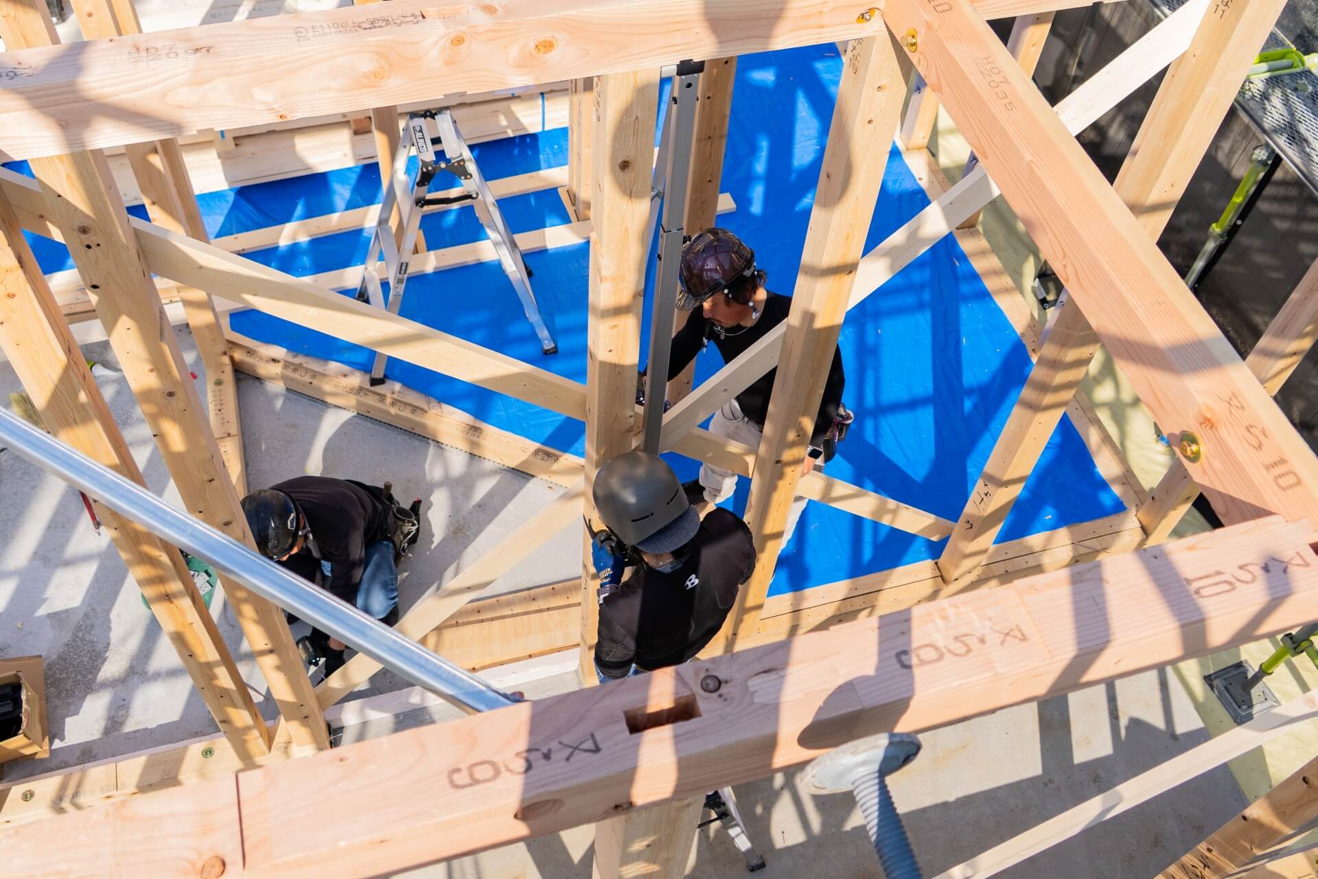 山梨県の住宅現場で、柱の建て込み作業を進める職人たちの様子。構造材の間から見える、現場の丁寧な手仕事の一場面。