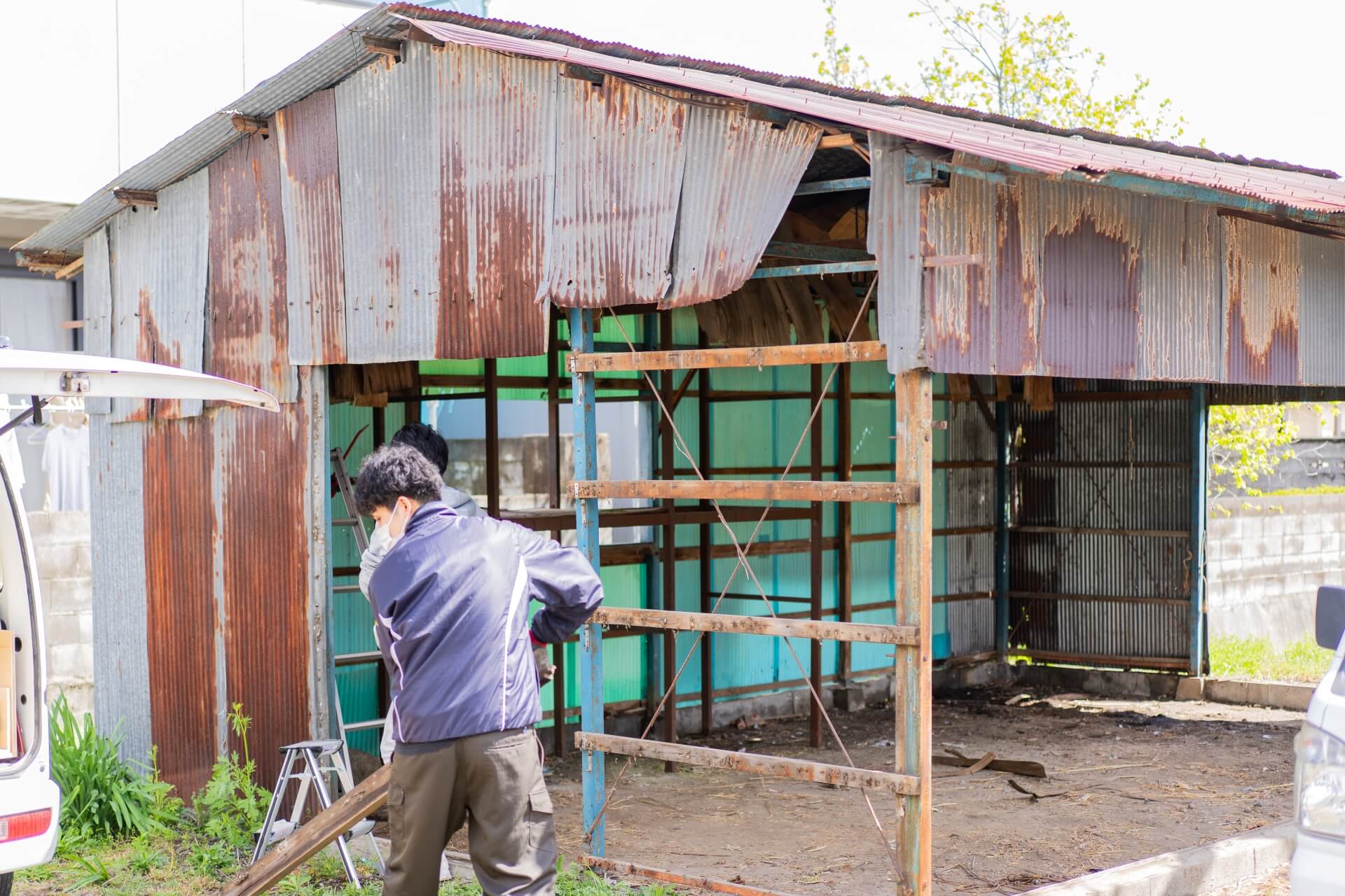 オーナー様と一緒に協力して古いトタン小屋を解体している様子。