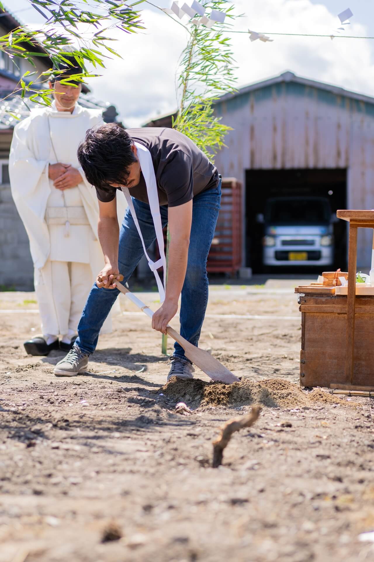 山梨県の地鎮祭で、鍬入れの儀を行う様子(神主と祭壇が背景に写る)