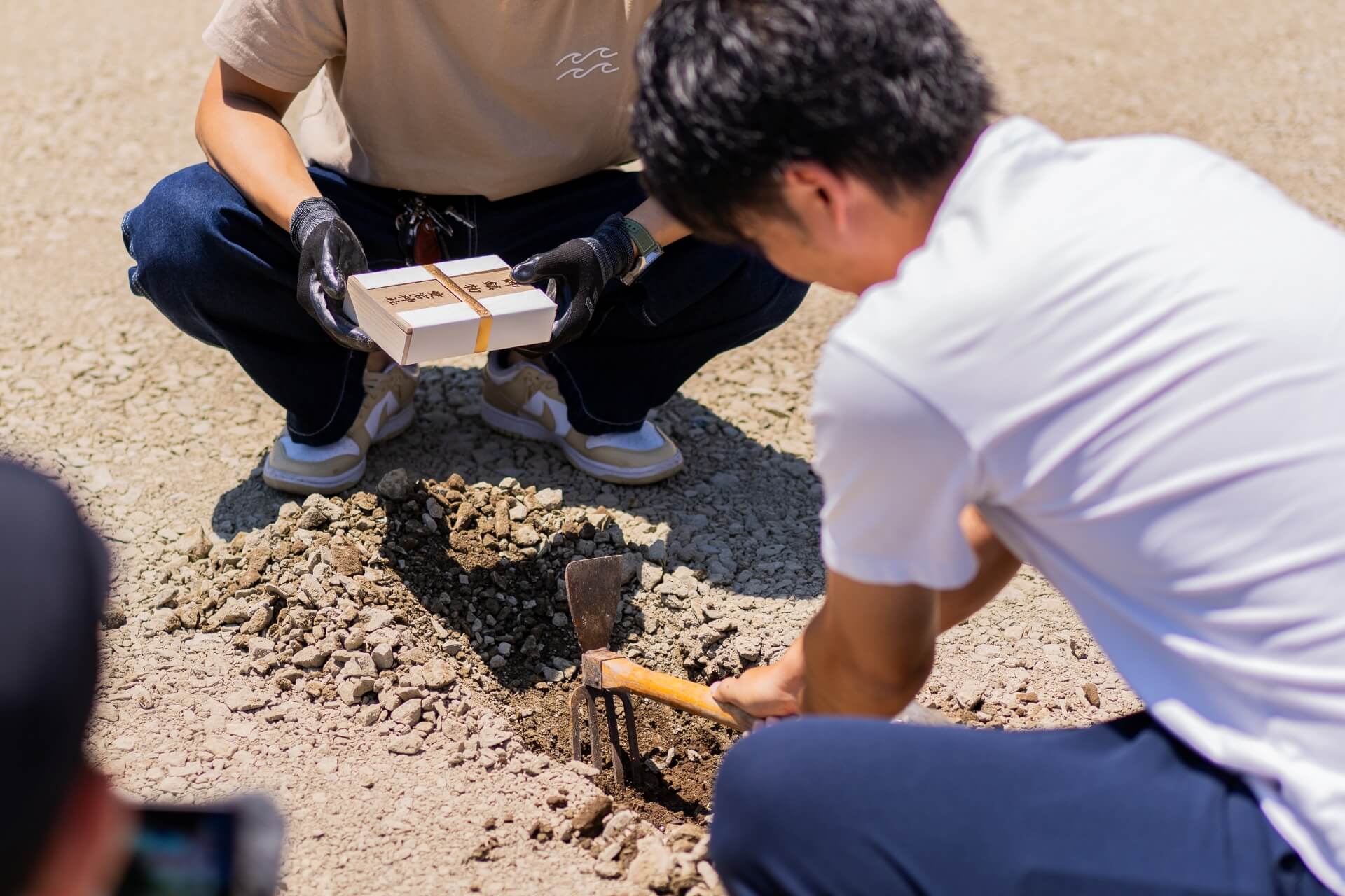 山梨県南アルプス市の現場、鍬(くわ)で土を掘り、鎮め物を納める準備をしている様子。