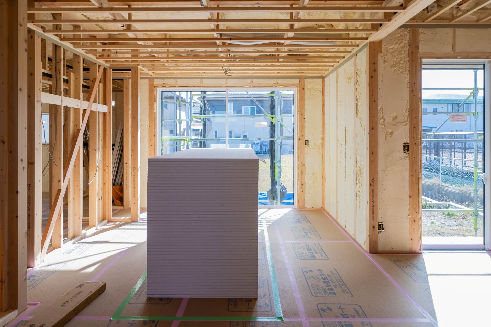 山梨県南アルプス市藤田の現場にて施工中の建物の中の様子。石膏ボードが積み上げられている。