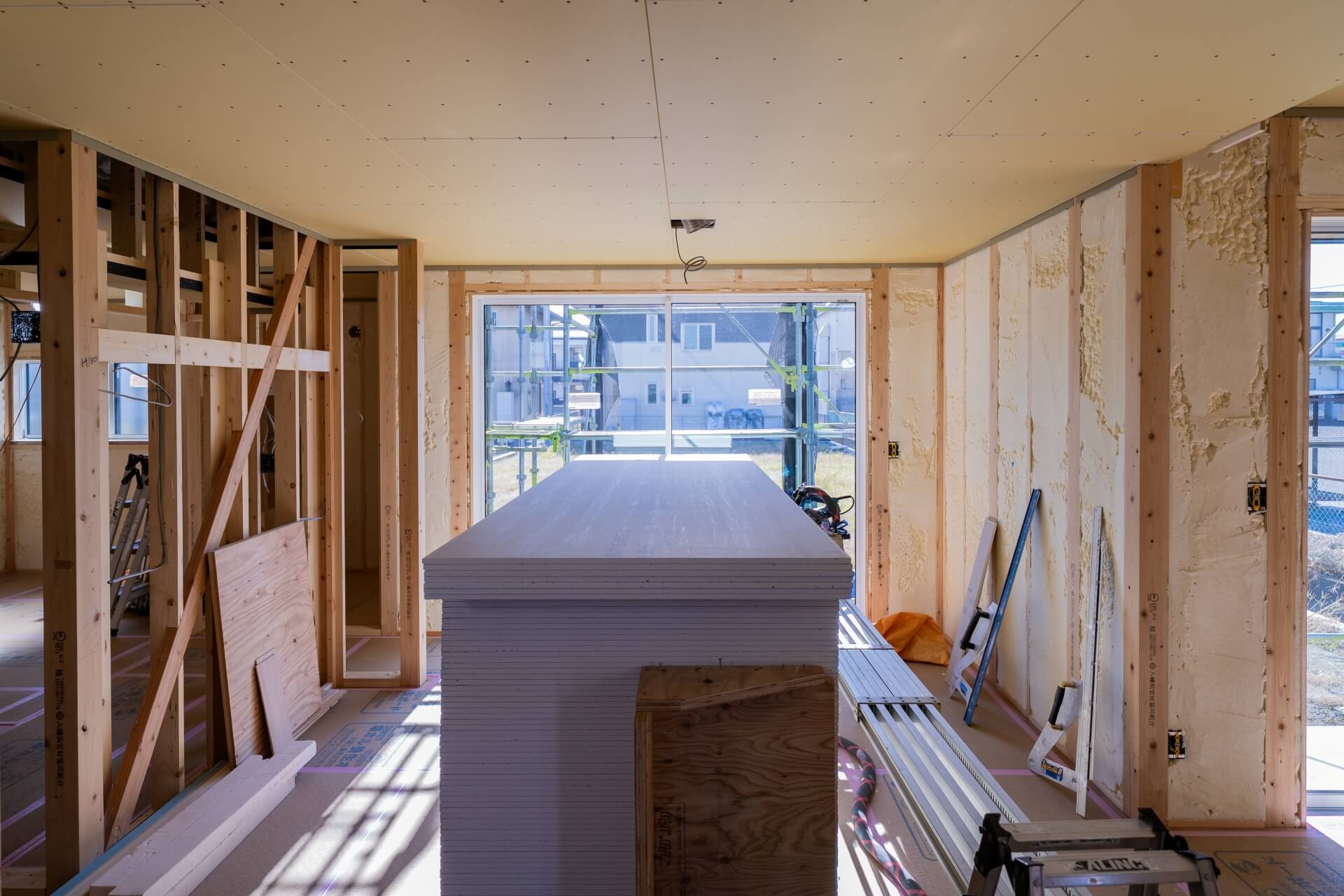 山梨県南アルプス市藤田の現場にて施工中の室内の様子。石膏ボードが山積みになっている。