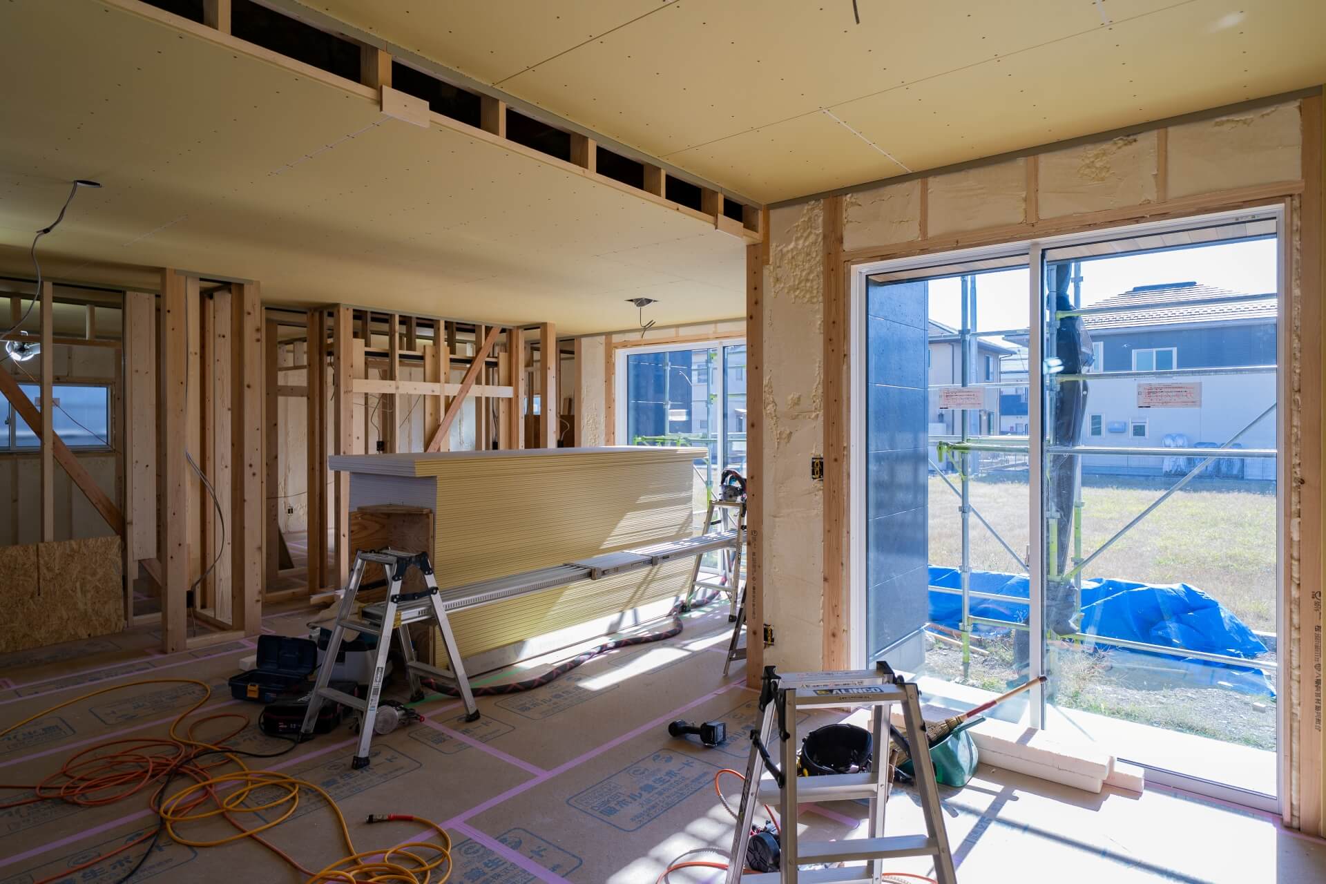 山梨県南アルプス市藤田の現場にて施工中の室内の様子。石膏ボードが山積みになっている。