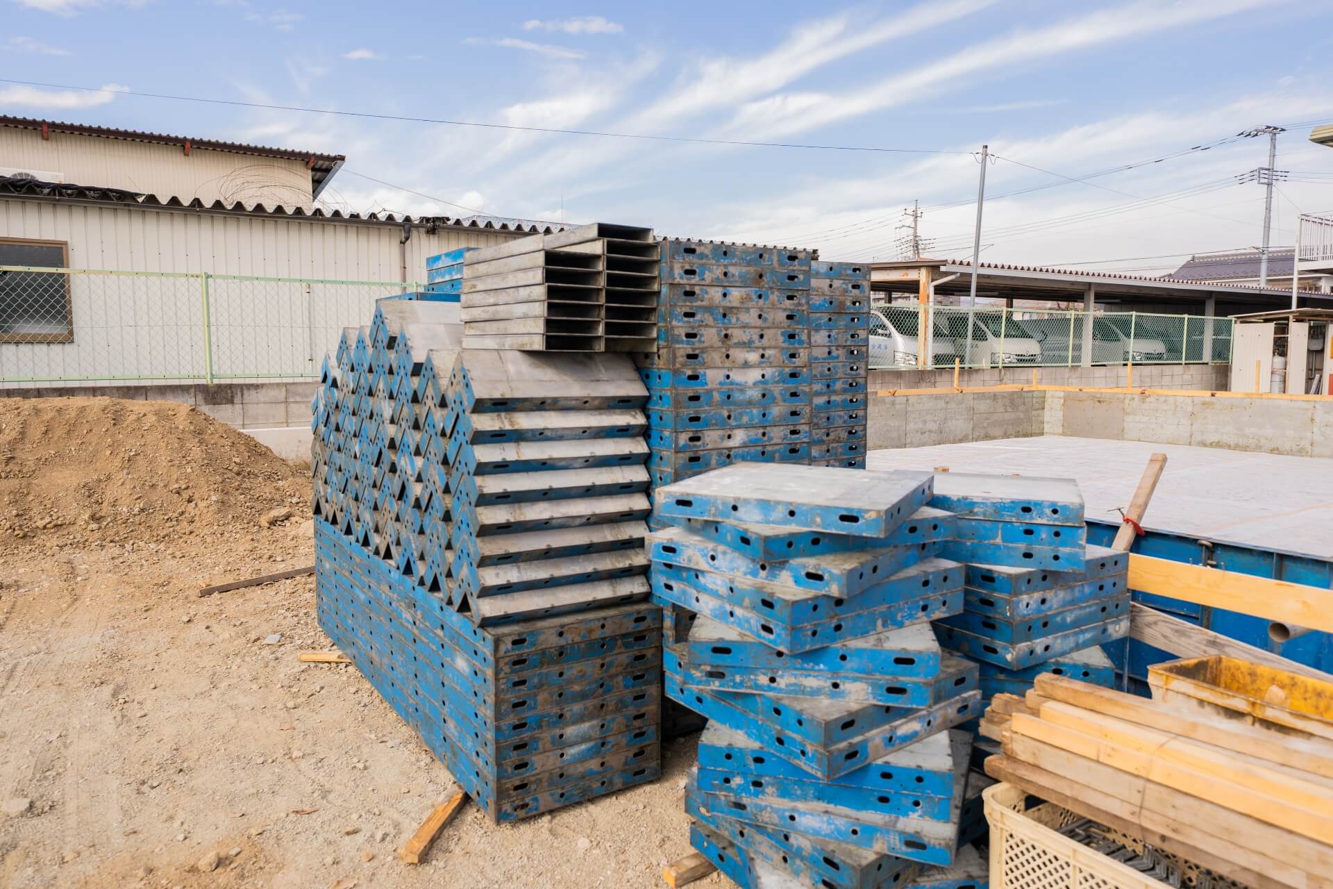 山梨県甲府市蓬沢の新築現場にて青い型枠パネルが整然と積み上げられた基礎工事現場の写真。