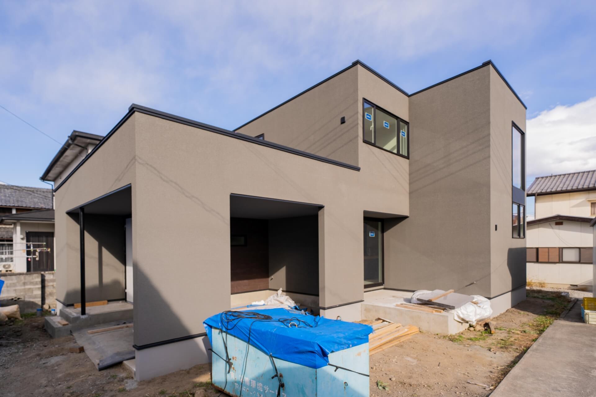 山梨県南アルプス市寺部の新築現場にてグレーの外観の建物。