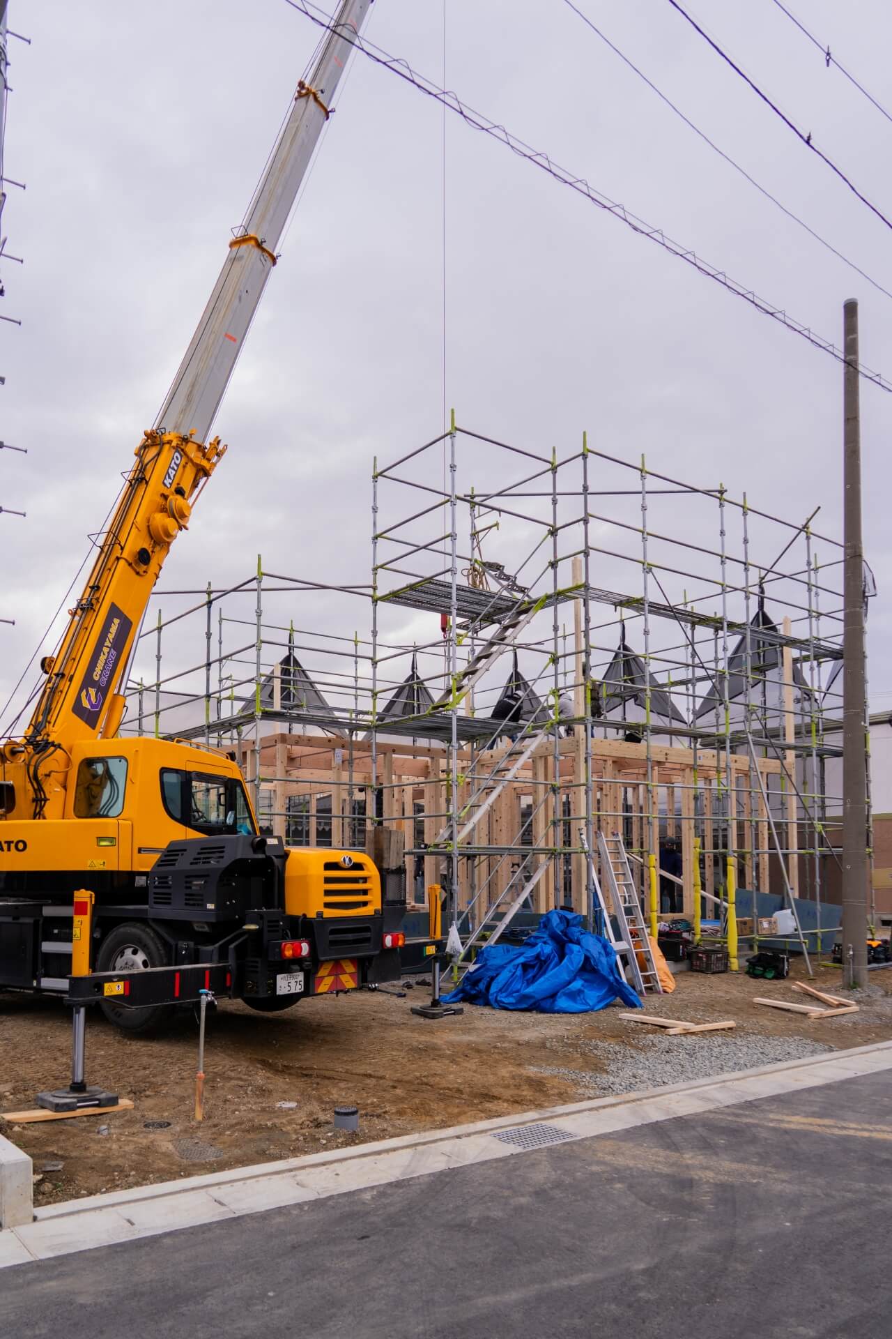 山梨県甲府市蓬沢の新築現場にて足場に囲まれた木造住宅の上棟工事中の外観。
