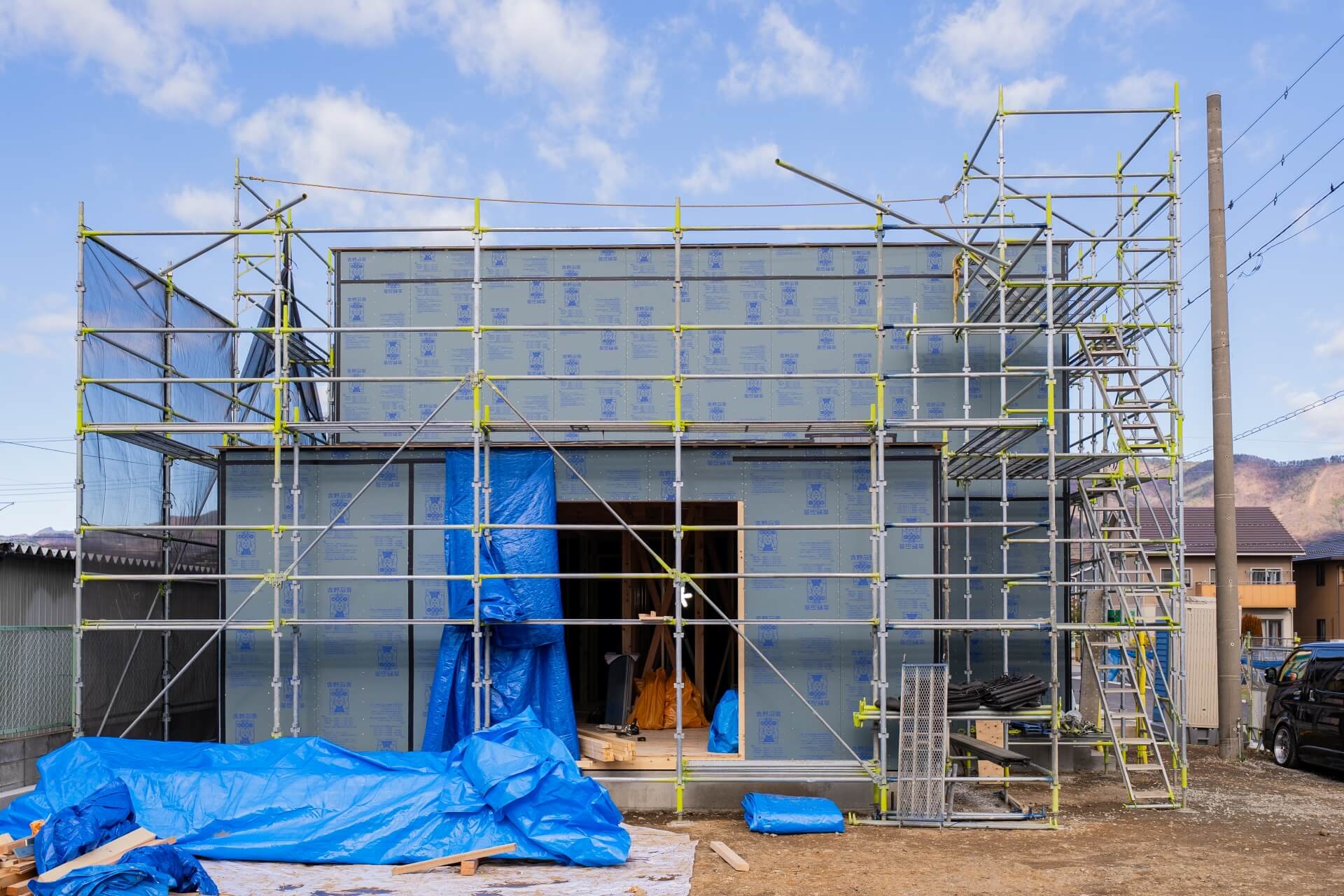 山梨県甲府市蓬沢の新築現場にて足場に囲まれた工事中の木造住宅の外観。