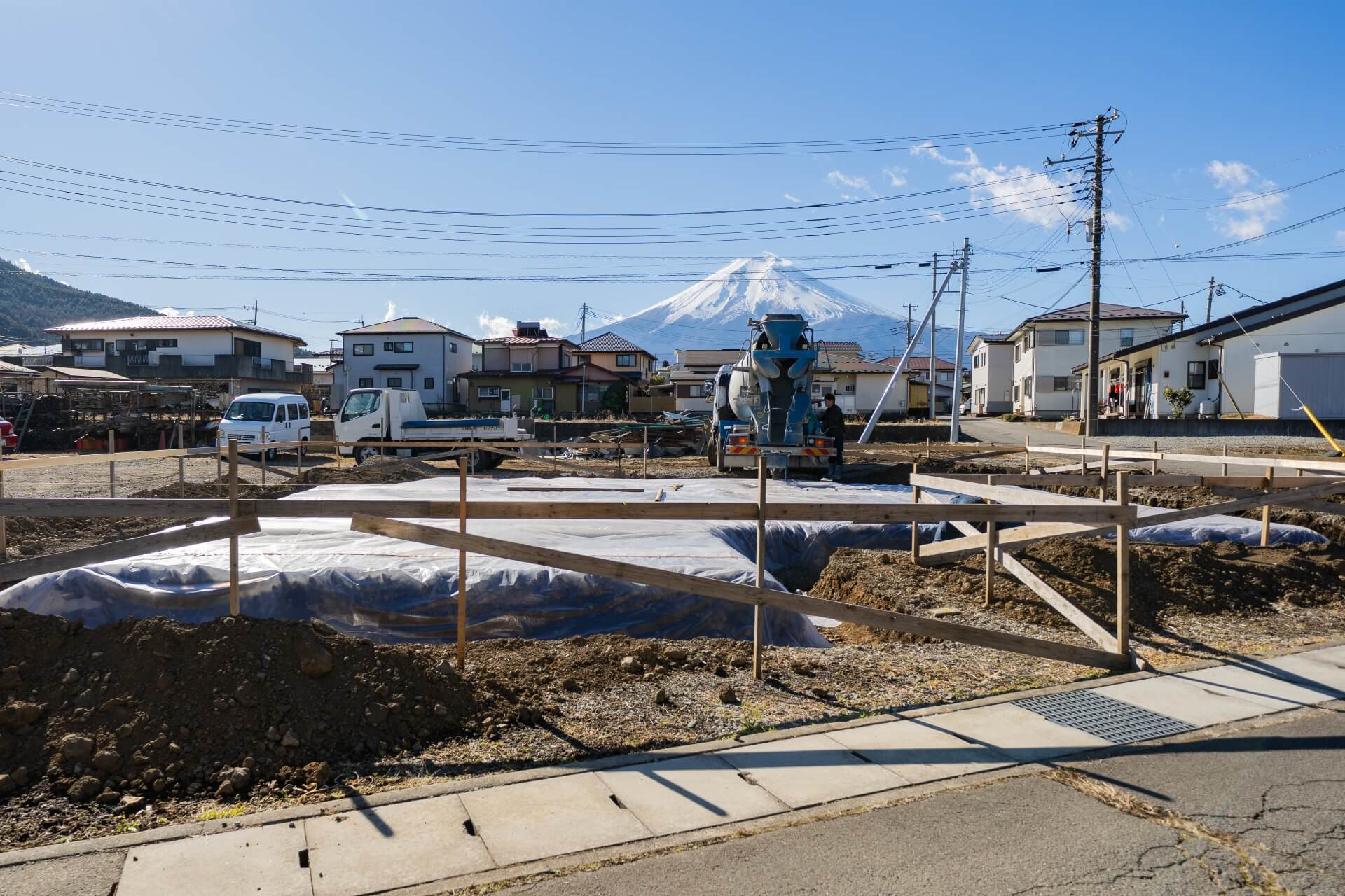 山梨県富士吉田市大明見の建築現場。基礎工事中の敷地の奥に富士山が見えるロケーション。住宅地の中でも開けた景色が広がる立地。