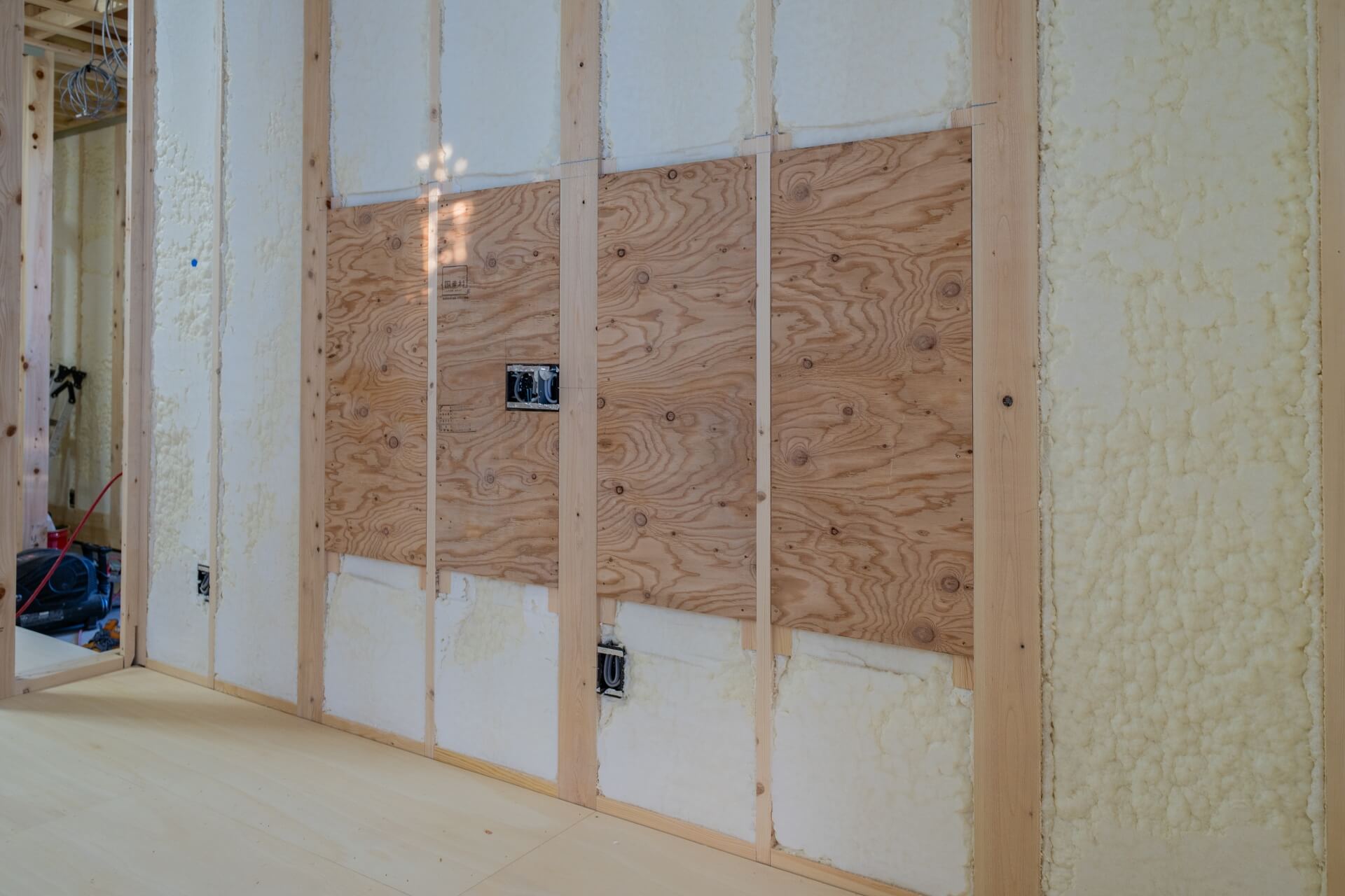 山梨県甲府市蓬沢の新築現場にて、断熱材と木造下地の壁に設備取付用の補強下地を施工している様子。