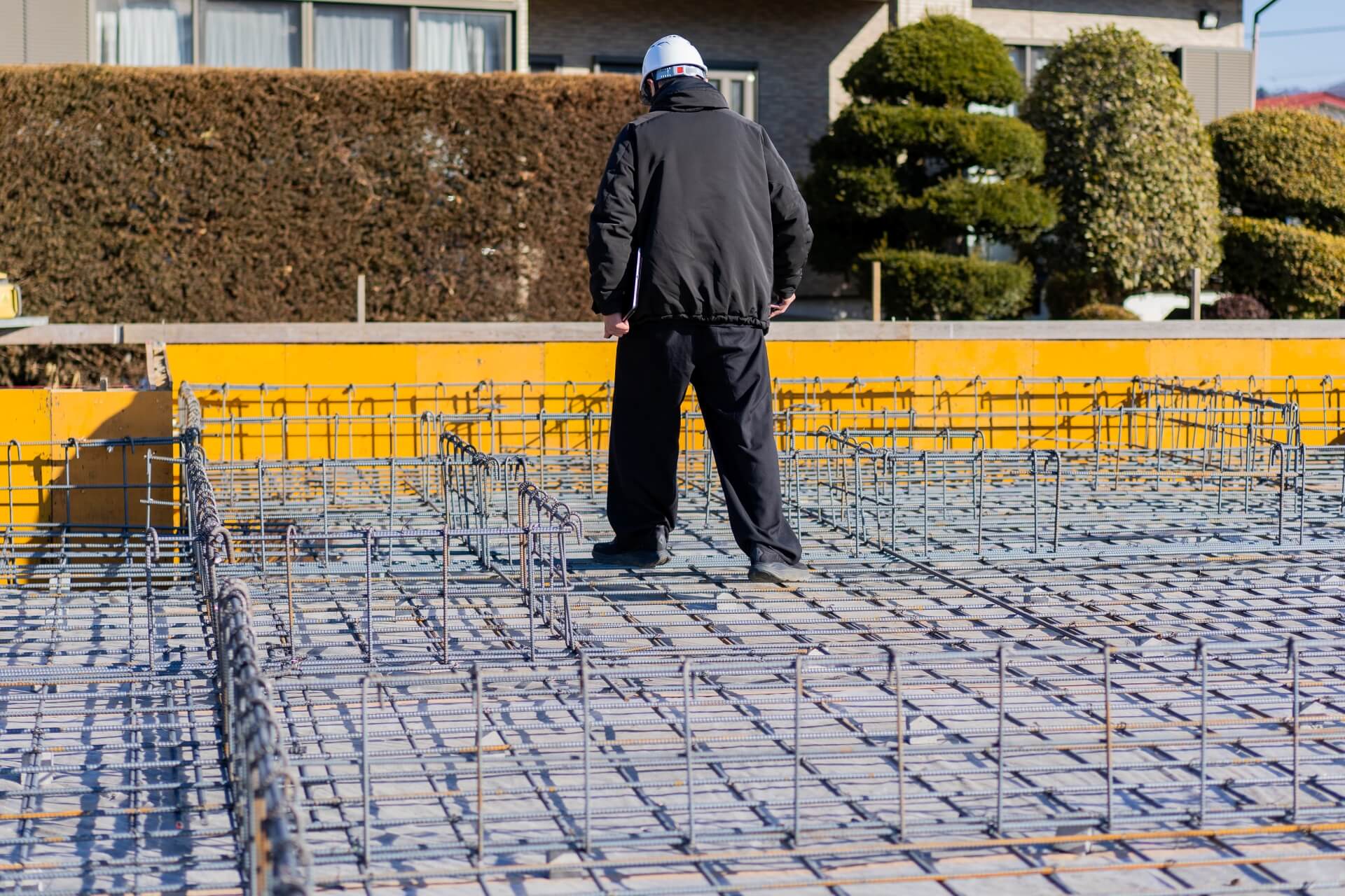 山梨県富士吉田市大明見の建築現場。基礎配筋の上を歩きながら確認作業を行う設計士。施工精度を細かくチェックしている工程。