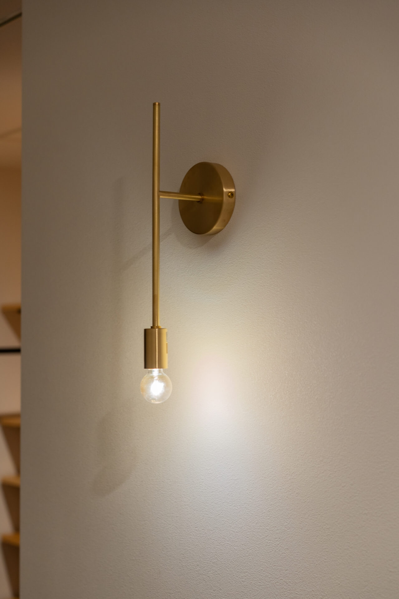 山梨県南アルプス市寺部の新築現場、真鍮のブラケットライトが壁に取り付けられた照明ディテール。シンプルなデザインと柔らかな光が空間を演出する。。