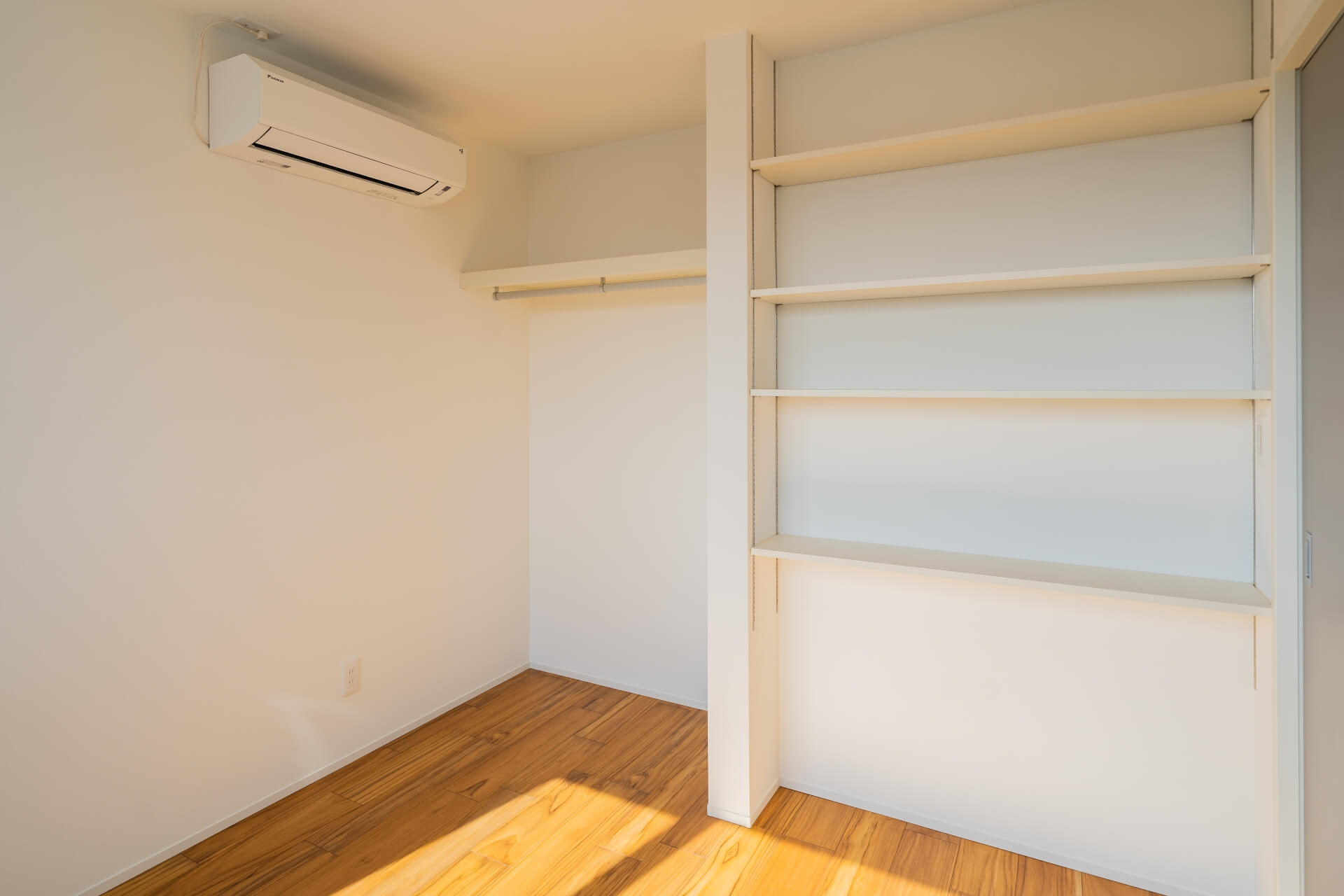 山梨県南アルプス市寺部の新築現場、エアコン上部に設置されたハンガーパイプと可動棚。限られた空間を有効活用した収納。