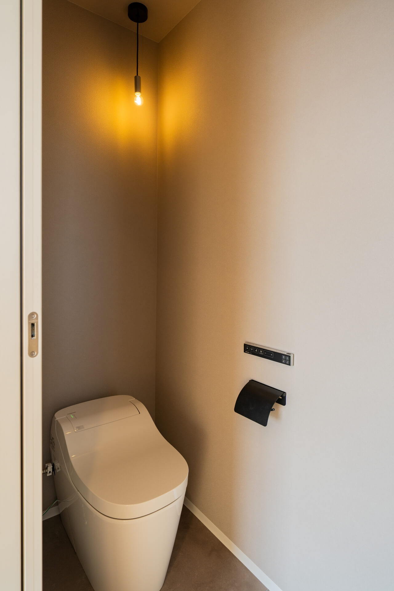 山梨県南アルプス市寺部の新築現場、ペンダント照明のあたたかい光に包まれたトイレ空間。シンプルで落ち着いた内装。