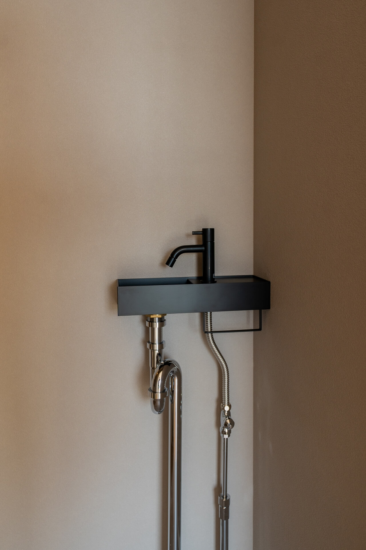 山梨県南アルプス市寺部の新築現場、ブラックのコンパクトな手洗いカウンターとシンプルな水栓。ミニマルなデザイン。