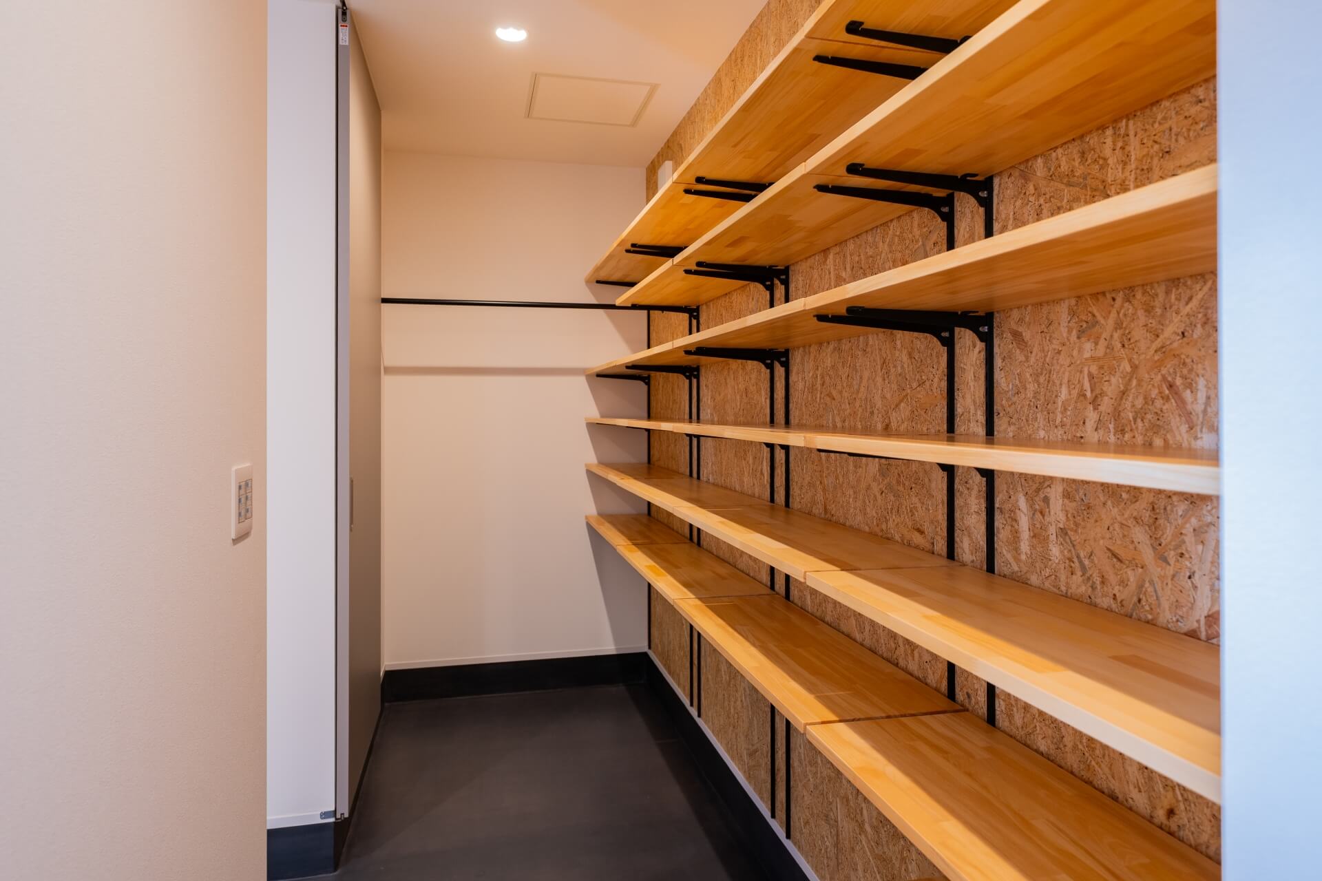 山梨県南アルプス市寺部の新築現場、奥まで続くシューズクローク。両側に棚があり、動線を確保した収納空間。