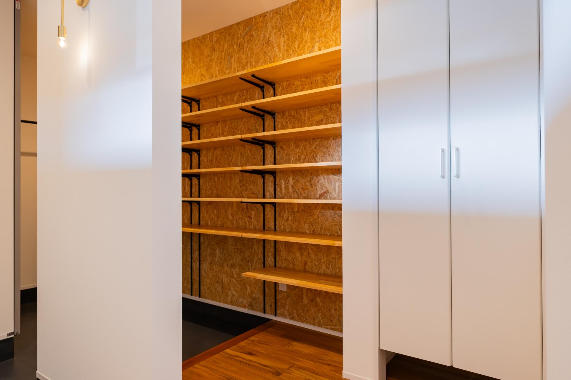 山梨県南アルプス市寺部の新築現場、壁一面に可動棚を設けたシューズクローク。奥行きのある収納スペース。