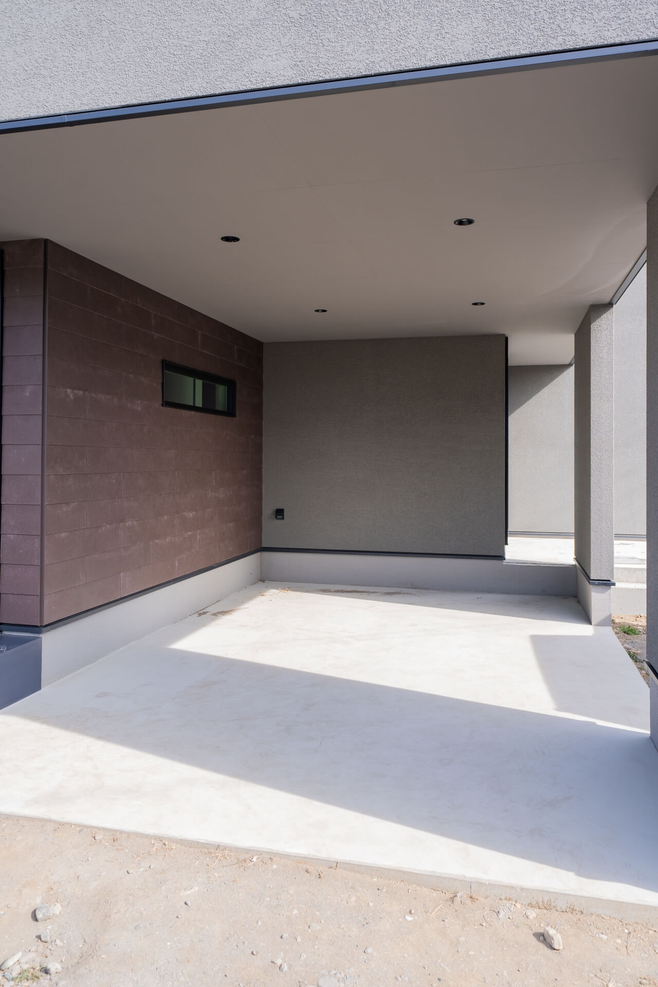 山梨県南アルプス市寺部の新築現場、OPENガレージ。軒天のダウンライトと異素材の外壁が印象的な半屋外空間。