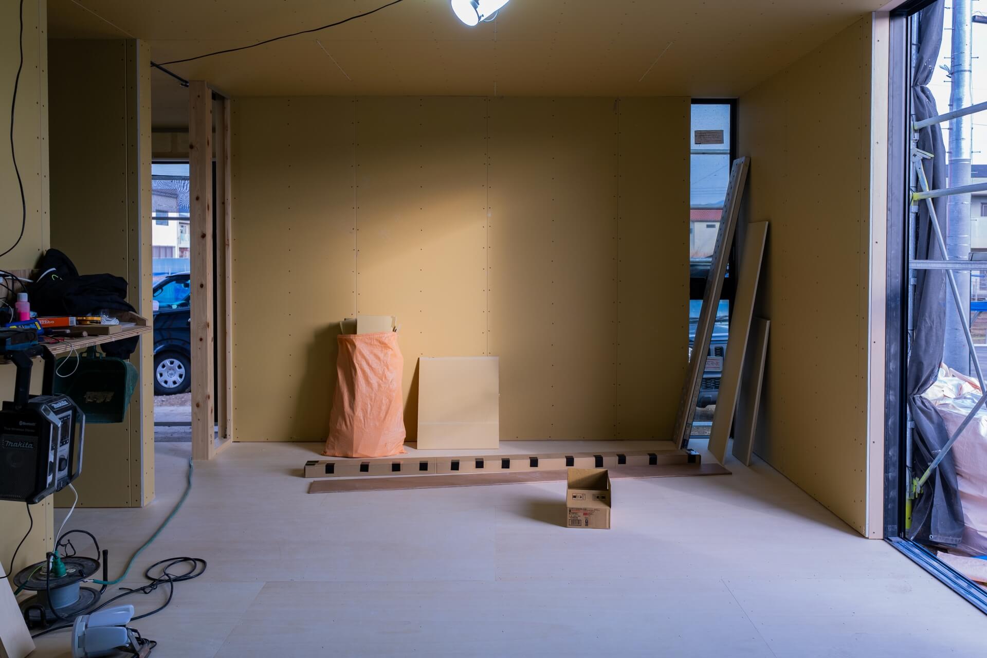 山梨県甲府市蓬沢の新築現場にて、石膏ボード施工後の室内に自然光が差し込む未完成の空間の様子。