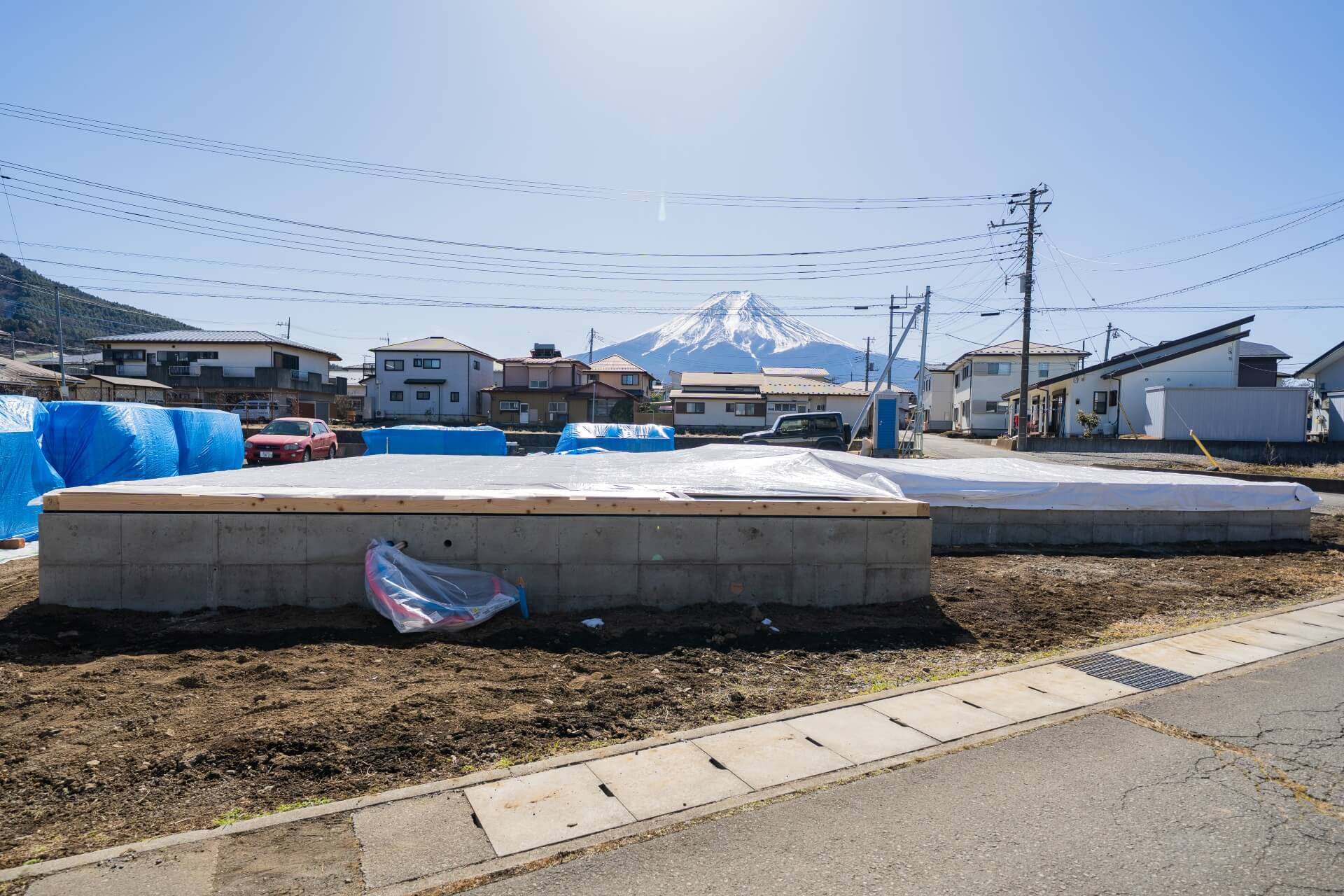 山梨県富士吉田市大明見の建築現場。コンクリート基礎が完成した住宅の敷地。奥には富士山が見え、これから上棟へ進む段階。