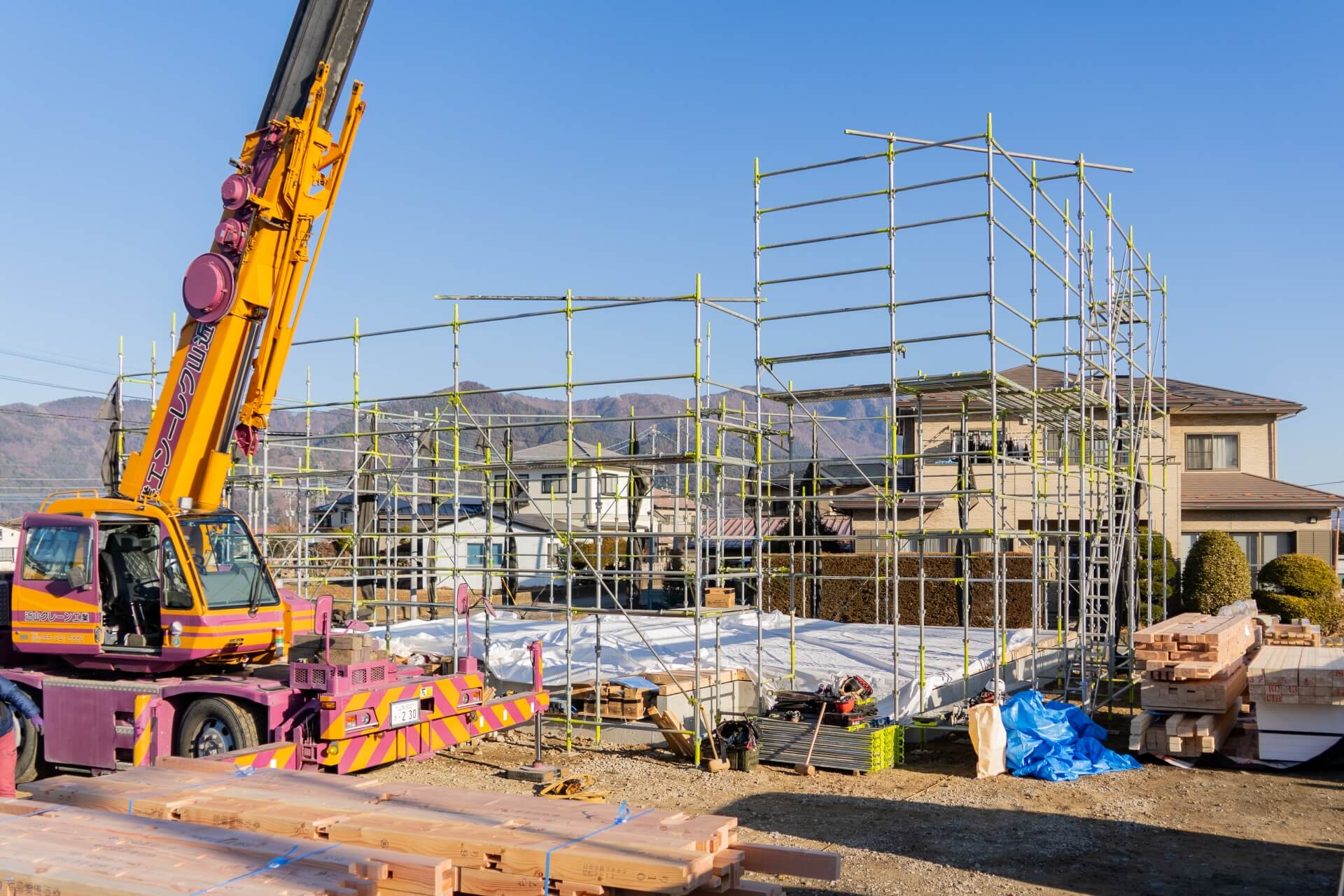 山梨県富士吉田市大明見の建築現場で足場と木材が準備された上棟前の様子。