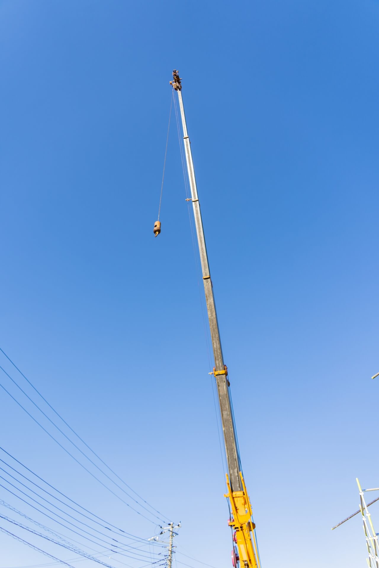 山梨県富士吉田市大明見の建築現場でクレーンが青空に伸びる上棟準備の様子。