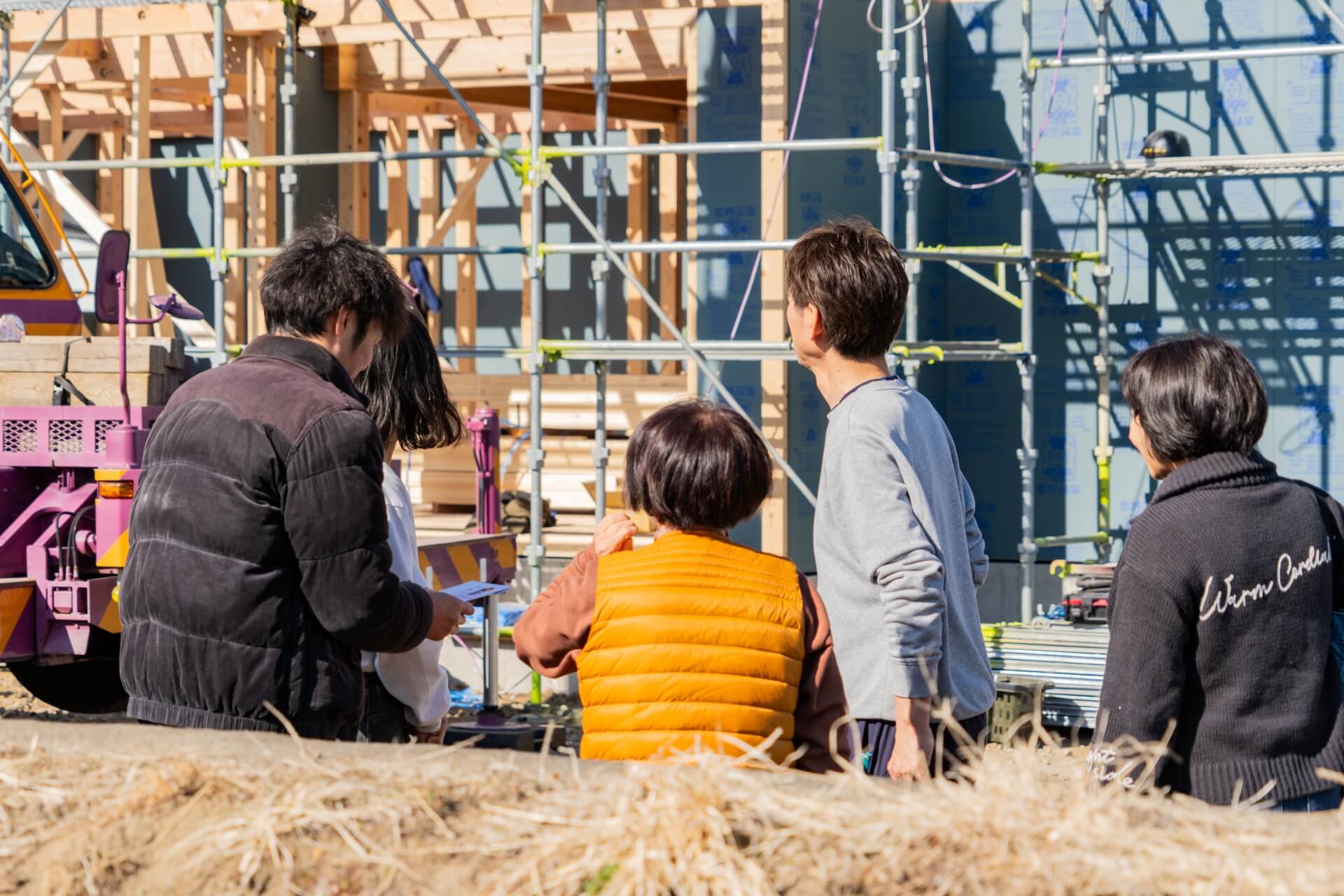 山梨県富士吉田市大明見の上棟現場で家族が建築中の家を見守る様子。