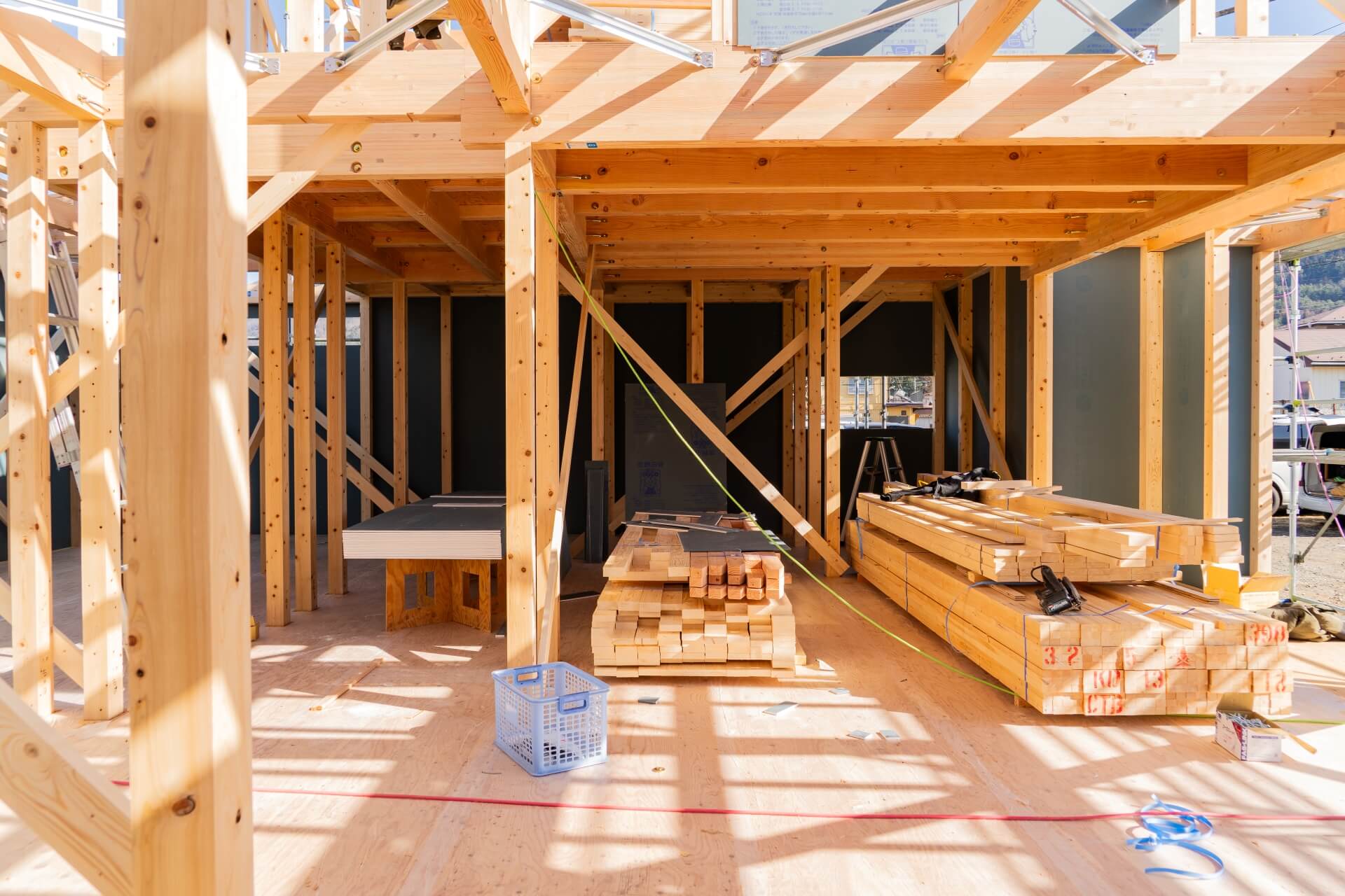 山梨県富士吉田市大明見の新築現場で木造構造内部と資材が並ぶ上棟中の様子。