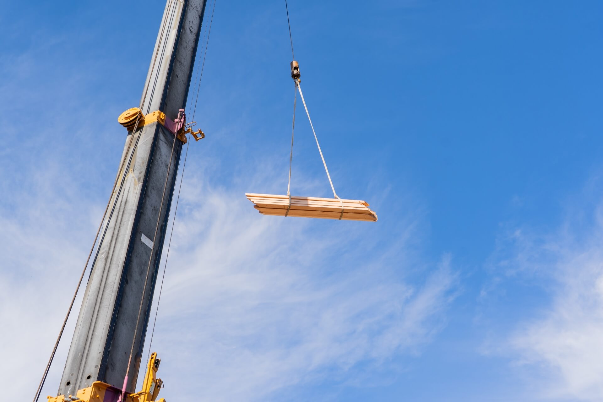 山梨県富士吉田市大明見の上棟現場でクレーンに吊られた木材が空中を移動する様子。