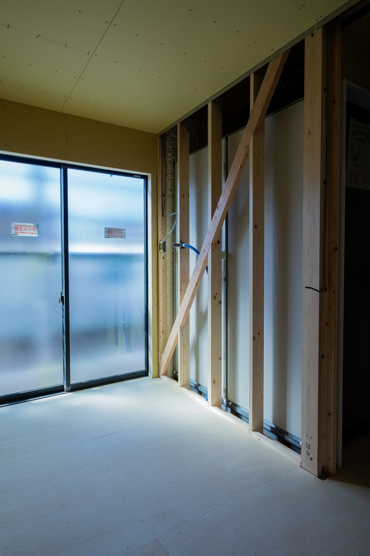 山梨県甲府市蓬沢の新築現場にて、筋交いの入った構造壁と窓からの自然光が差し込む内部空間の様子。