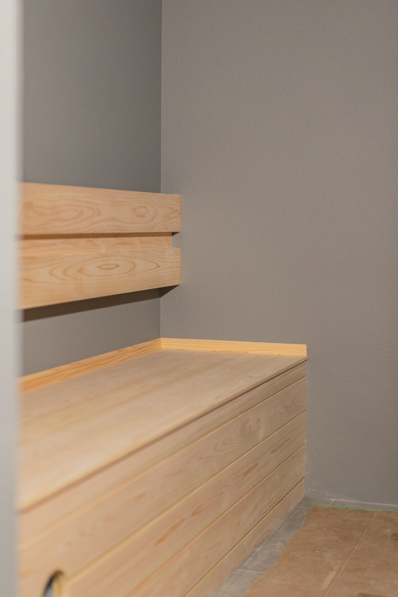 山梨県富士ケ嶺で建築中のヴィラの無垢材で造作されたベンチとグレーの壁が調和したサウナ。