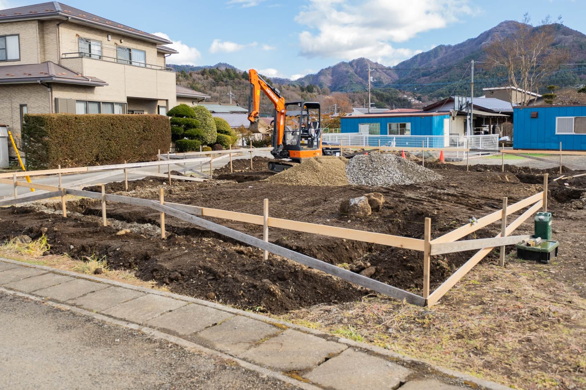 山梨県富士吉田市大明見の建築現場。周囲には住宅と山並みが広がる落ち着いた環境。