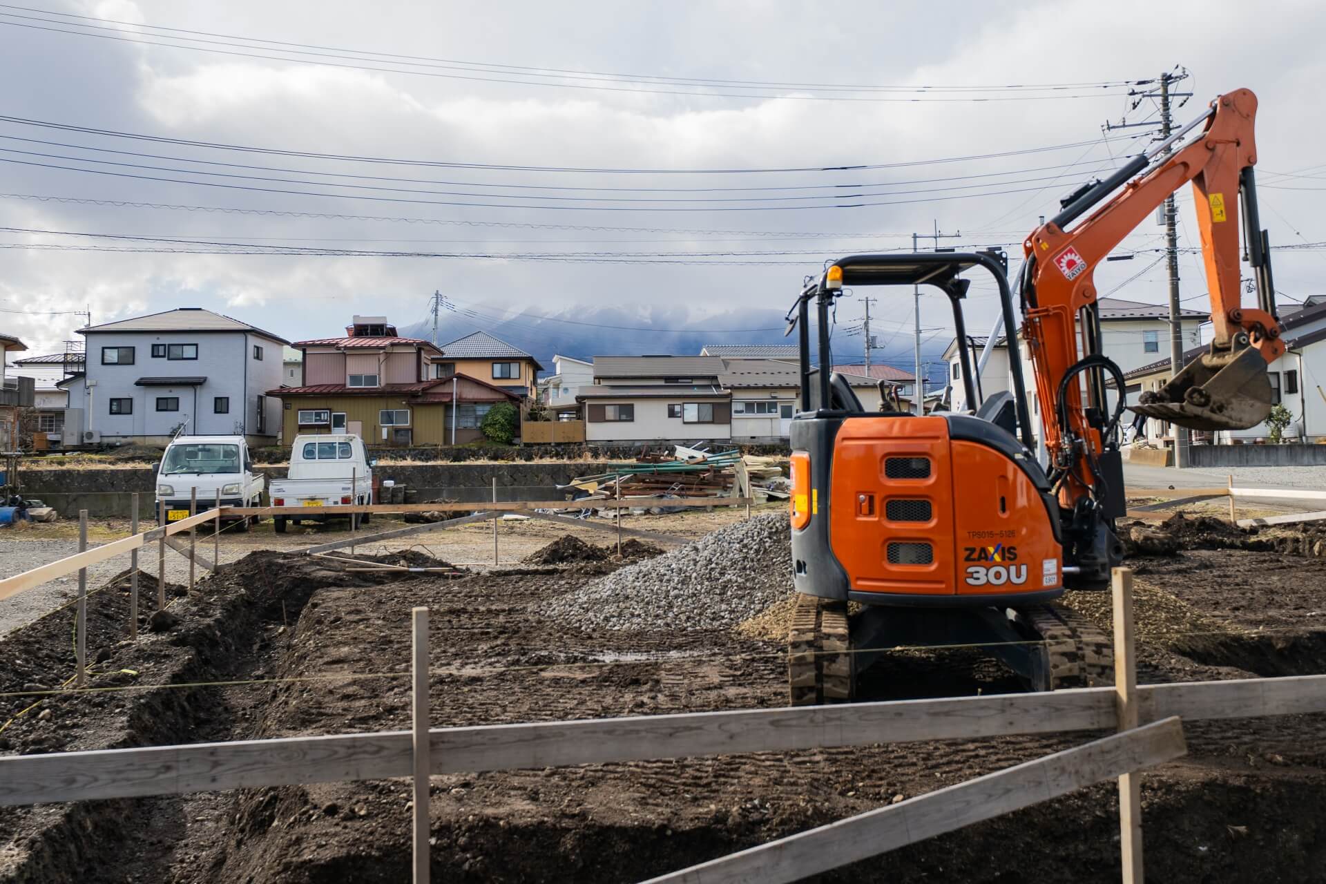 山梨県富士吉田市大明見の建築現場の基礎工事中の敷地。重機と砕石が配置され、これから建物が形づくられていく段階。