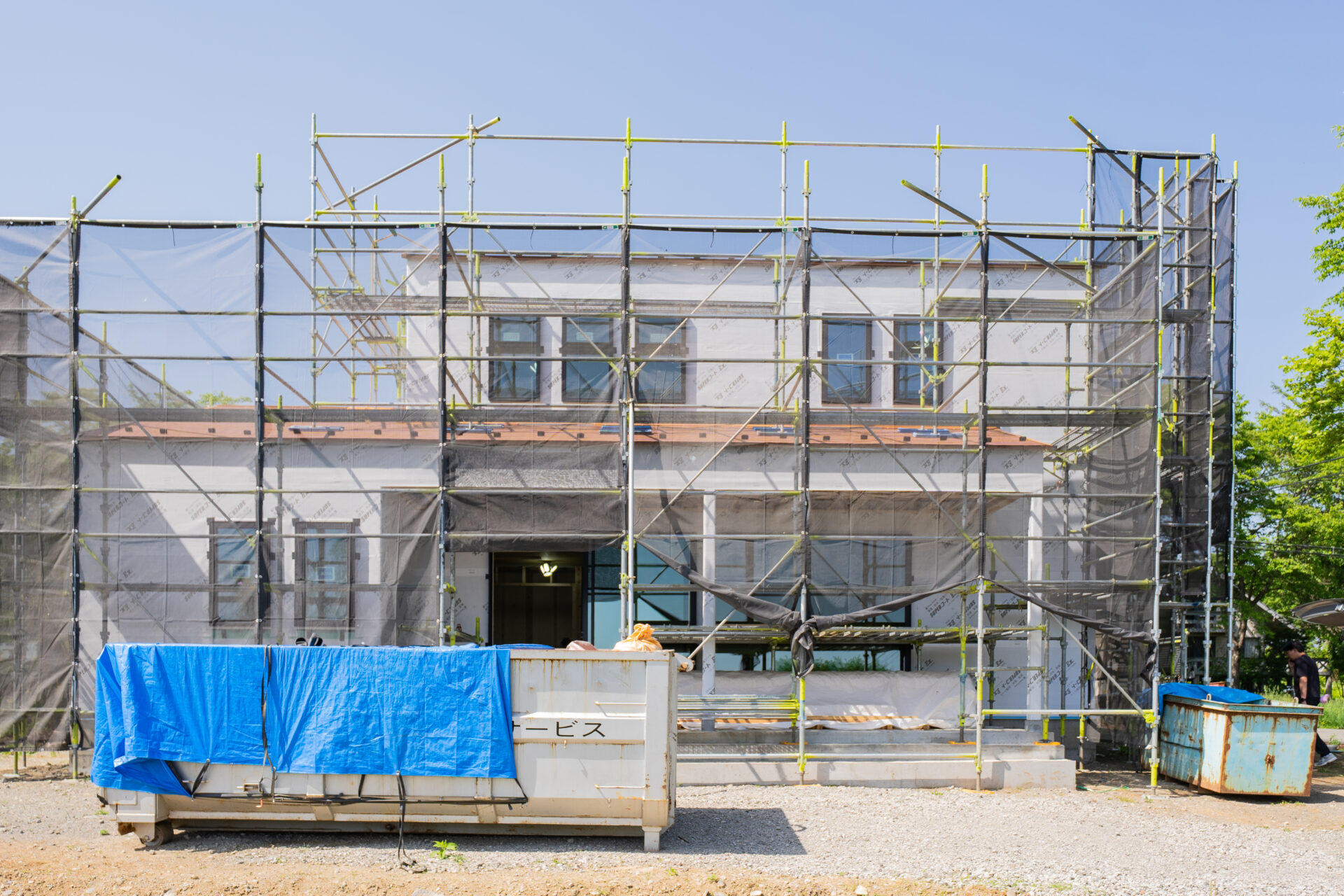 山梨県北杜市大泉町西井出の建築現場の施工中の外壁の様子。防水シートが貼られ、足場がかかっている。