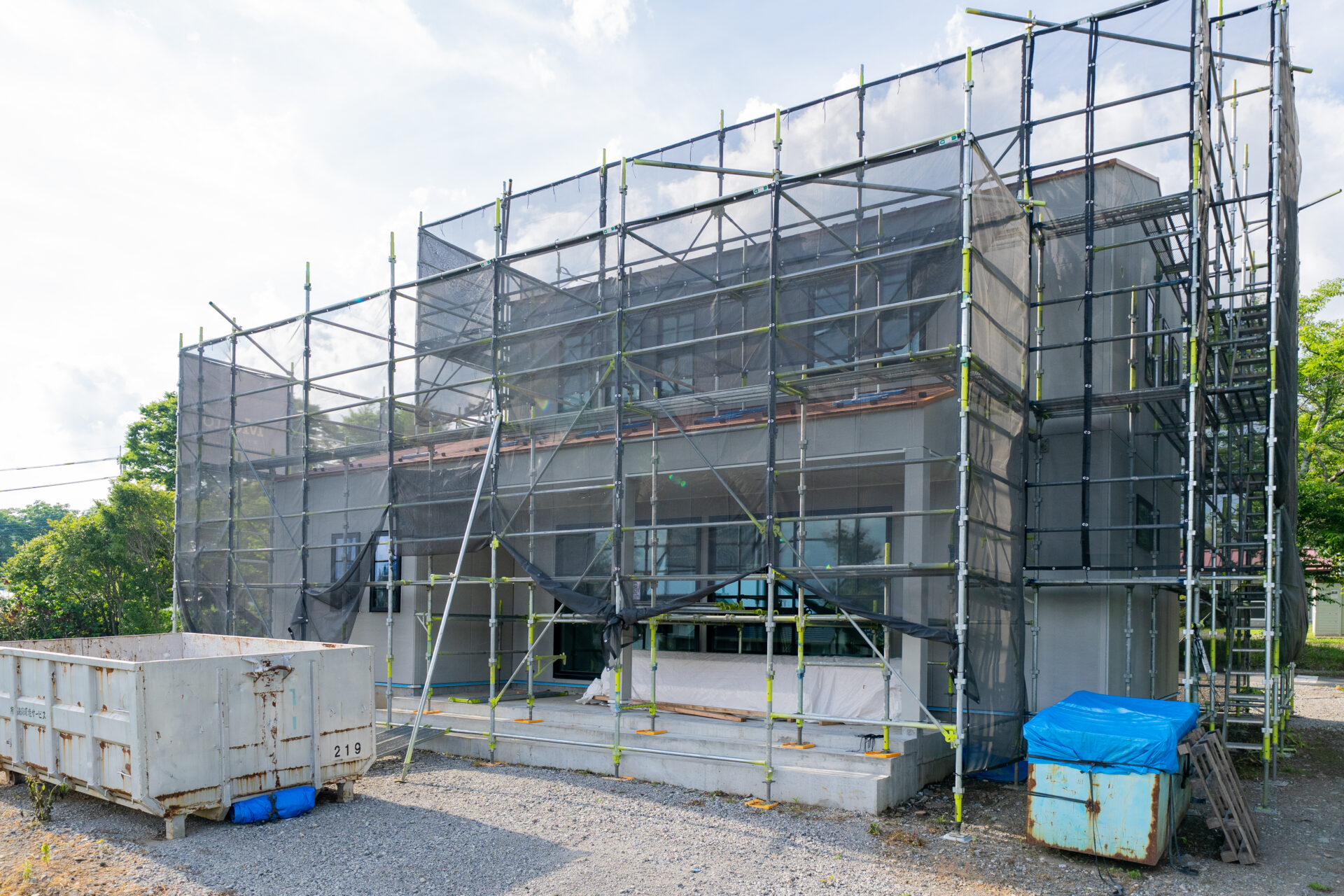 山梨県北杜市大泉町西井出の建築現場で外壁下地材の施工がされた建物。現場には足場が組まれている。