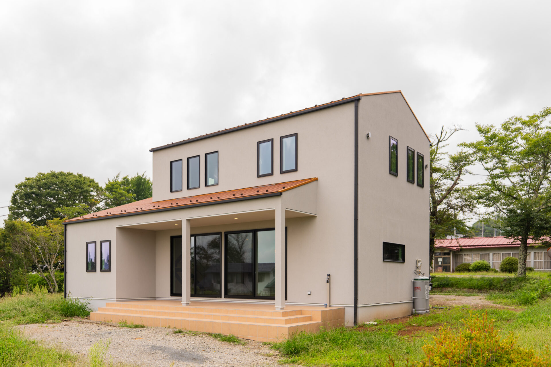 北杜市大泉町西井出の建築現場。ベージュの塗り壁とオレンジ系の屋根がやわらかな印象の外観。